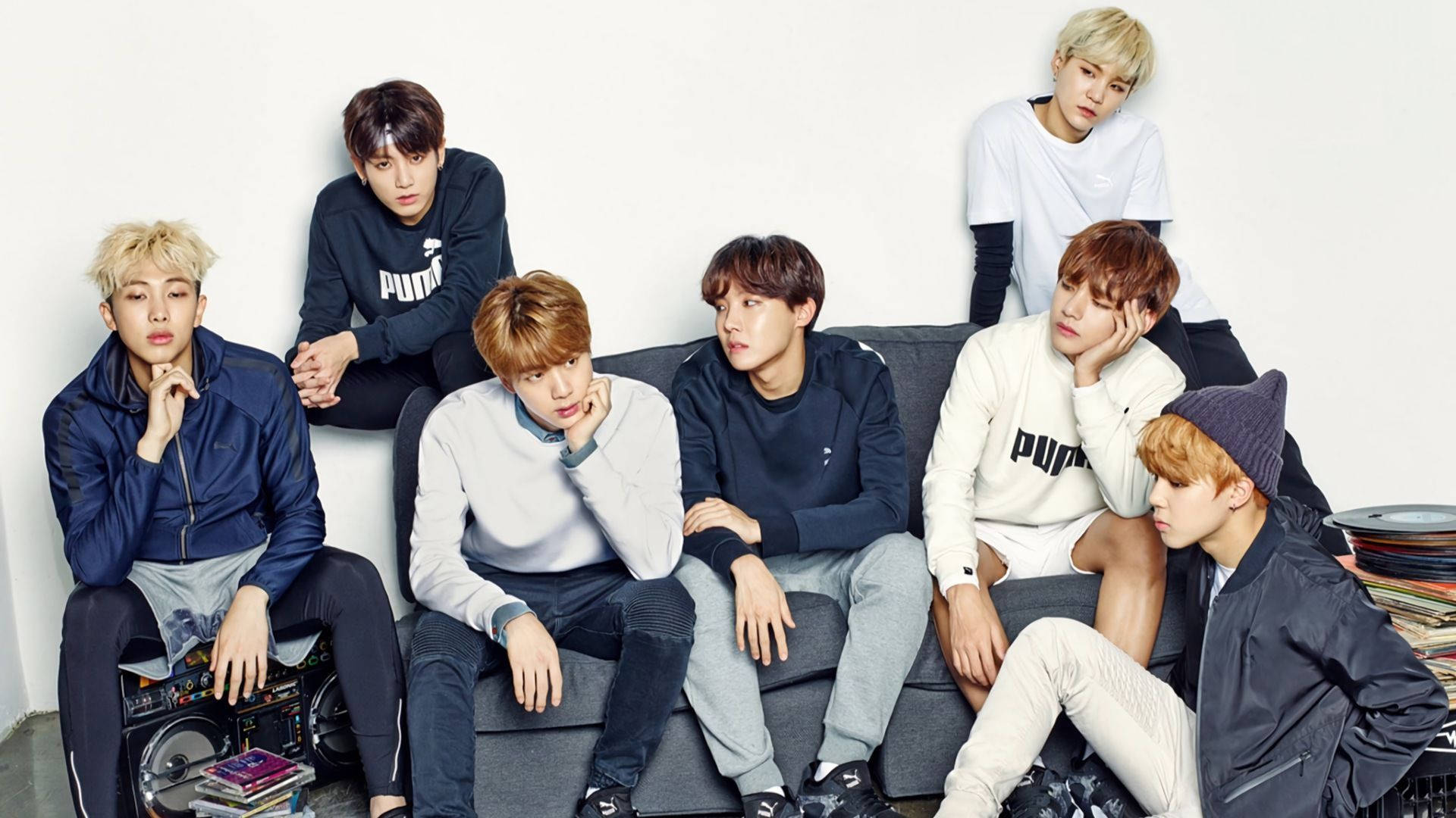 Група BTS на диван в синьо и бяло Тапет