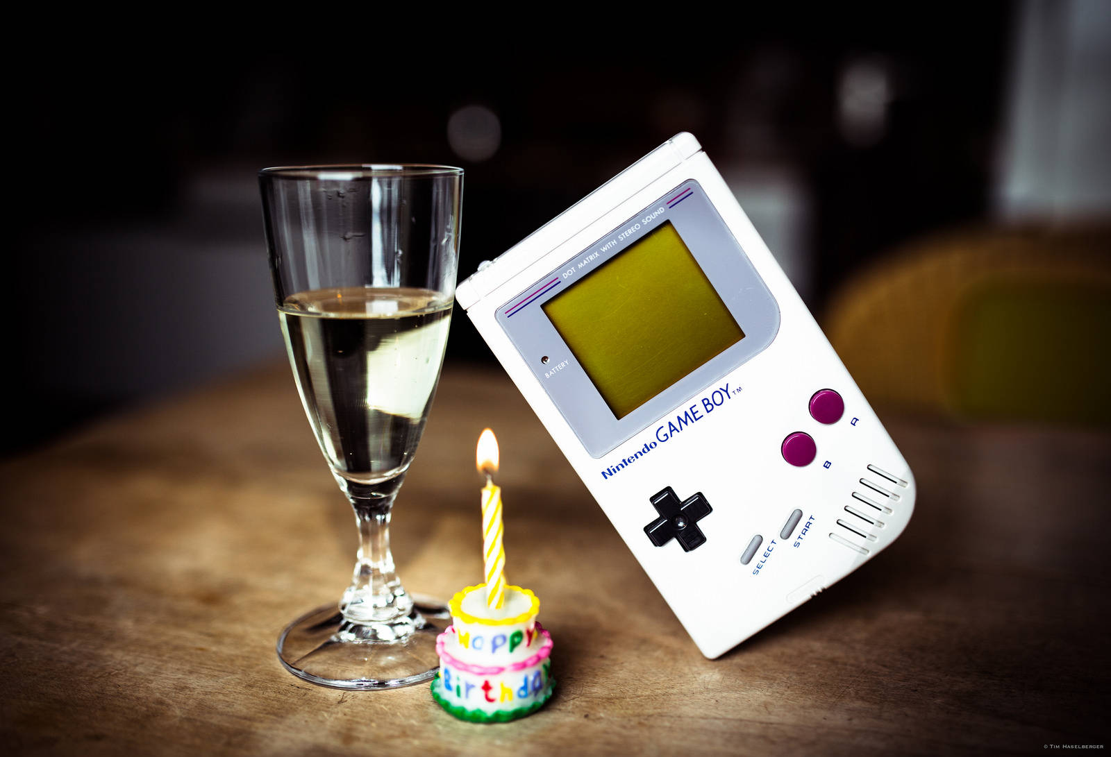 Винтажна реплика на Game Boy, изложена на стъклена маса с парче торта Тапет