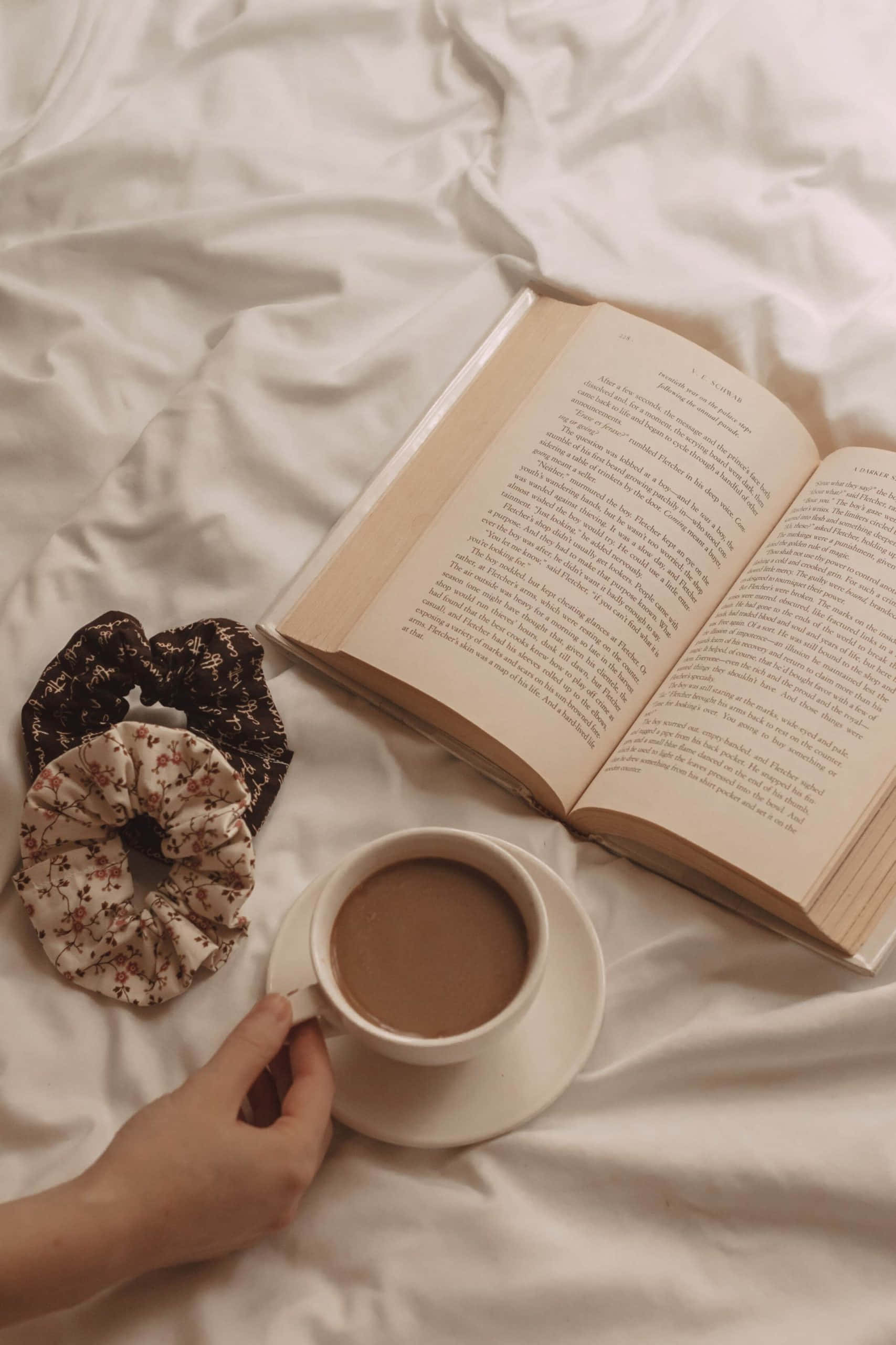 Женска ръка, държаща книга и чаша кафе Тапет
