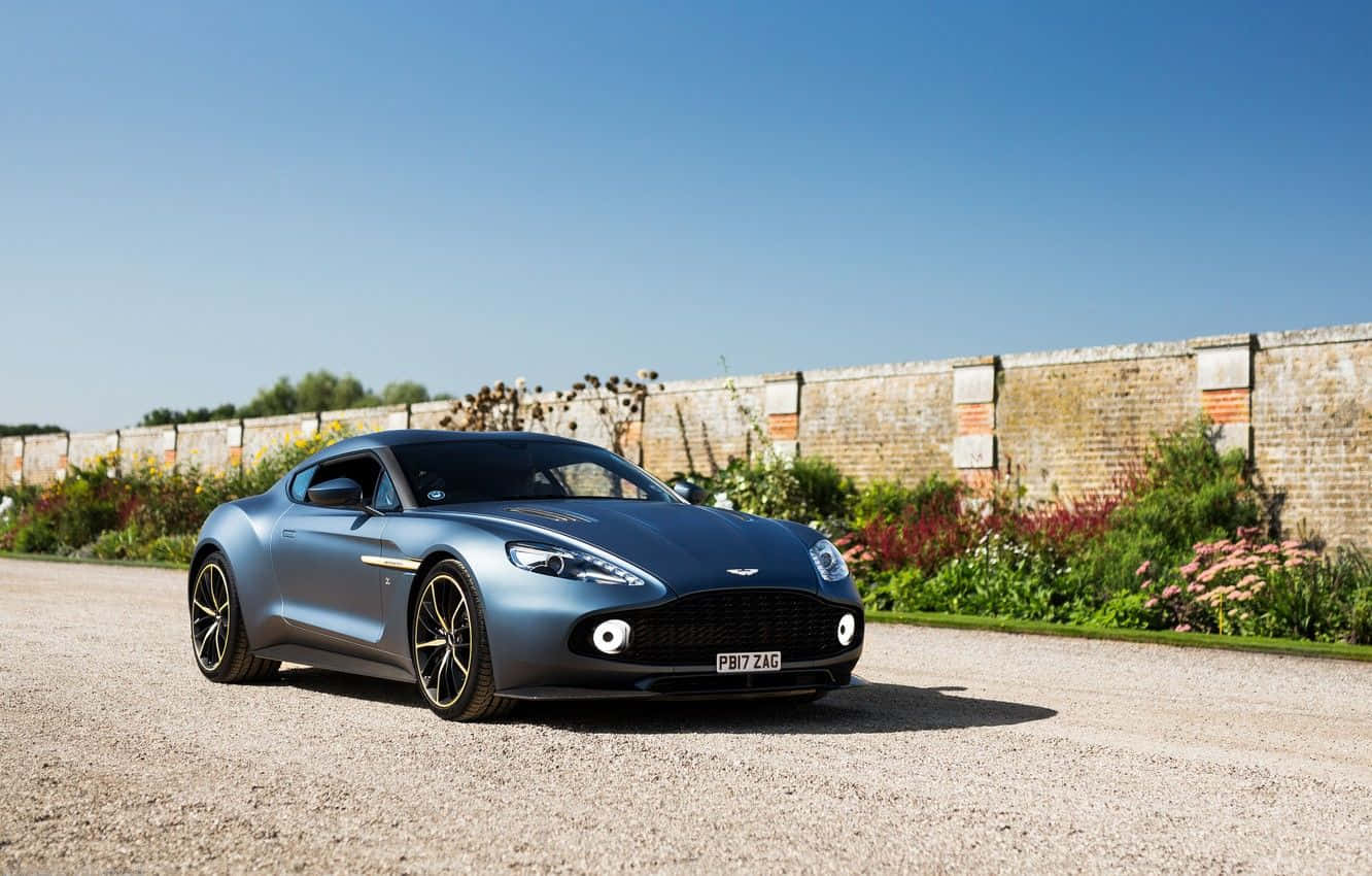 Зашемляващ Aston Martin Vanquish в движение по живописен път Тапет