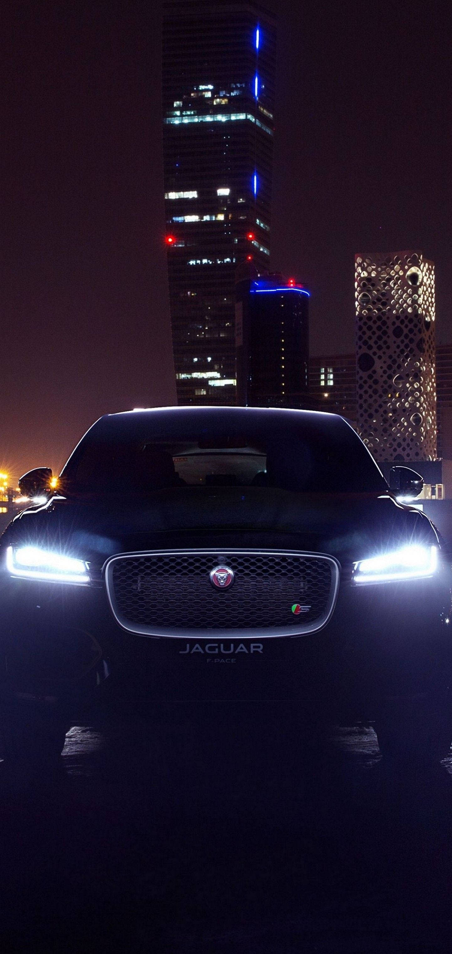 Изживейте силата и елегантността на кола Jaguar през нощ Тапет