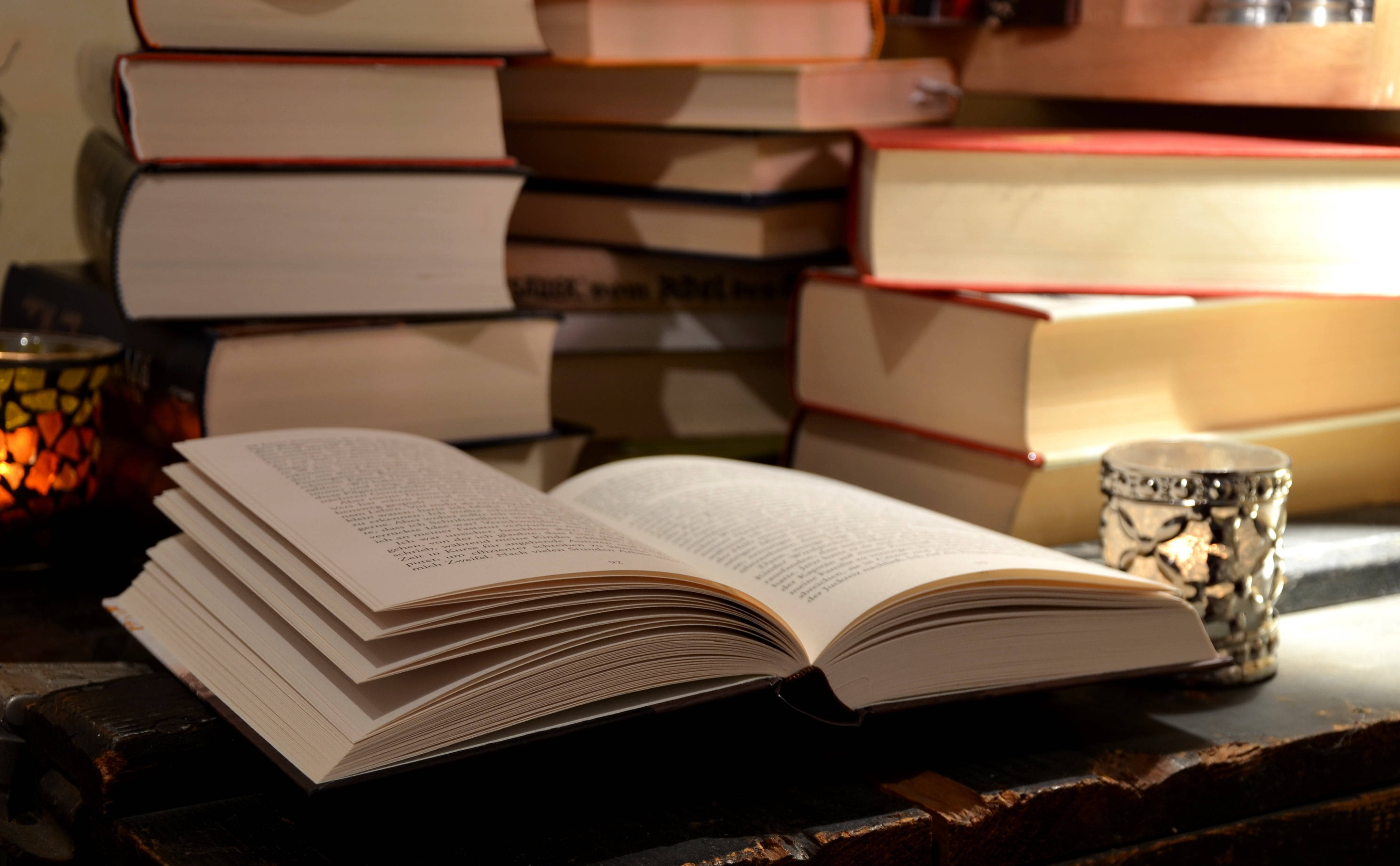 Отворена книга на бюро, заобиколена от други справочници Тапет