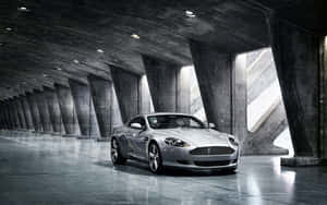 Aston Martin DB9 крузиращ през живописен градски пейзаж — Steam Deck OLED Тапет