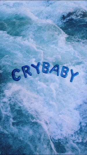 Готина синя естетична тапет с големи балони букви, които казват „Crybaby“, плаващи върху син океан или море.