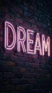 Неонова табела с надпис 'DREAM' на тухлена стена през нощ, мрачна и артистична. — iPad Тапет