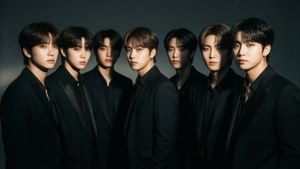 BTS в елегантни черни костюми с драматично ноар осветление.